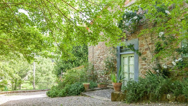 A stone building with a green door, surrounded by lush greenery and gravel paths. - Charm, comfort, relax at il Bracconiere, part of il Cavato, typical farmhouse
, (Poggio Alla Croce)