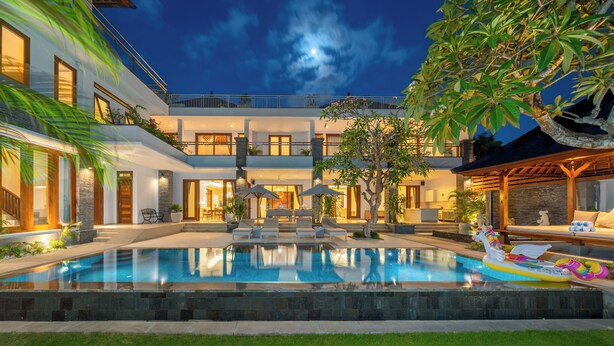 A modern hotel with a swimming pool, outdoor seating, and a well-maintained garden.