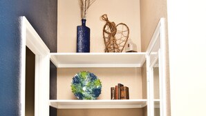 A narrow hallway with white shelving units displaying various decorative items. - "The Indigo" A little bit country, close to town.  New, clean and fresh looking (Kyle)