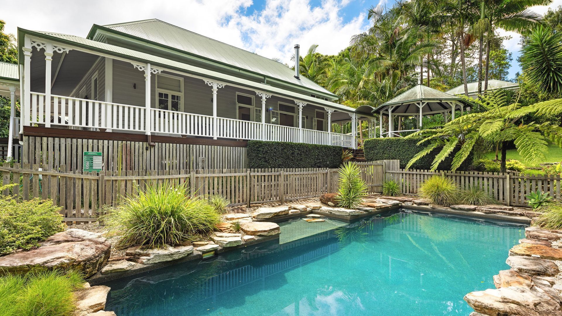 A house with a pool surrounded by rocks and plants.