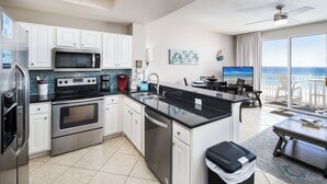 A modern kitchen with white cabinets, stainless steel appliances, and a large island.