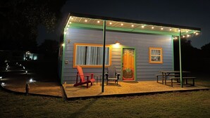 A small house with a porch, a red chair, and a table.