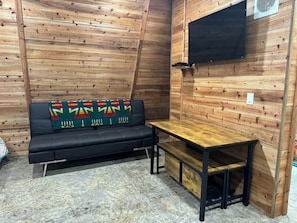 Relax in this compact room with a leather sofa, flat-screen TV, and small wooden table.