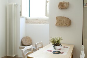 Un espace repas comprenant une table, des chaises, une plante en pot et des éléments décoratifs en pierre sur les murs.