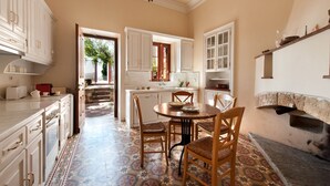 A spacious kitchen with white cabinets, a dining table with chairs, and a patterned floor.