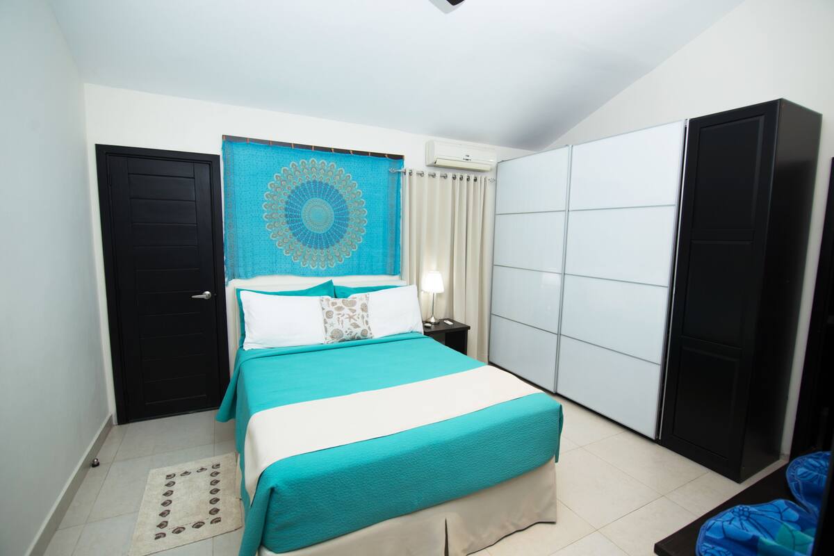 A bedroom with a bed, a nightstand, a wardrobe, and a door.