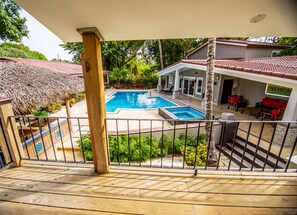 A wooden deck with a pool and a covered patio area. - Colibri Boutique Hotel (Sosúa)