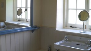 Een badkamer met een bad, een wastafel met spiegel en een raam met uitzicht.