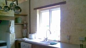 Een kleine keuken met een ingebouwde wasmachine, een spoelbak en een raam erboven.