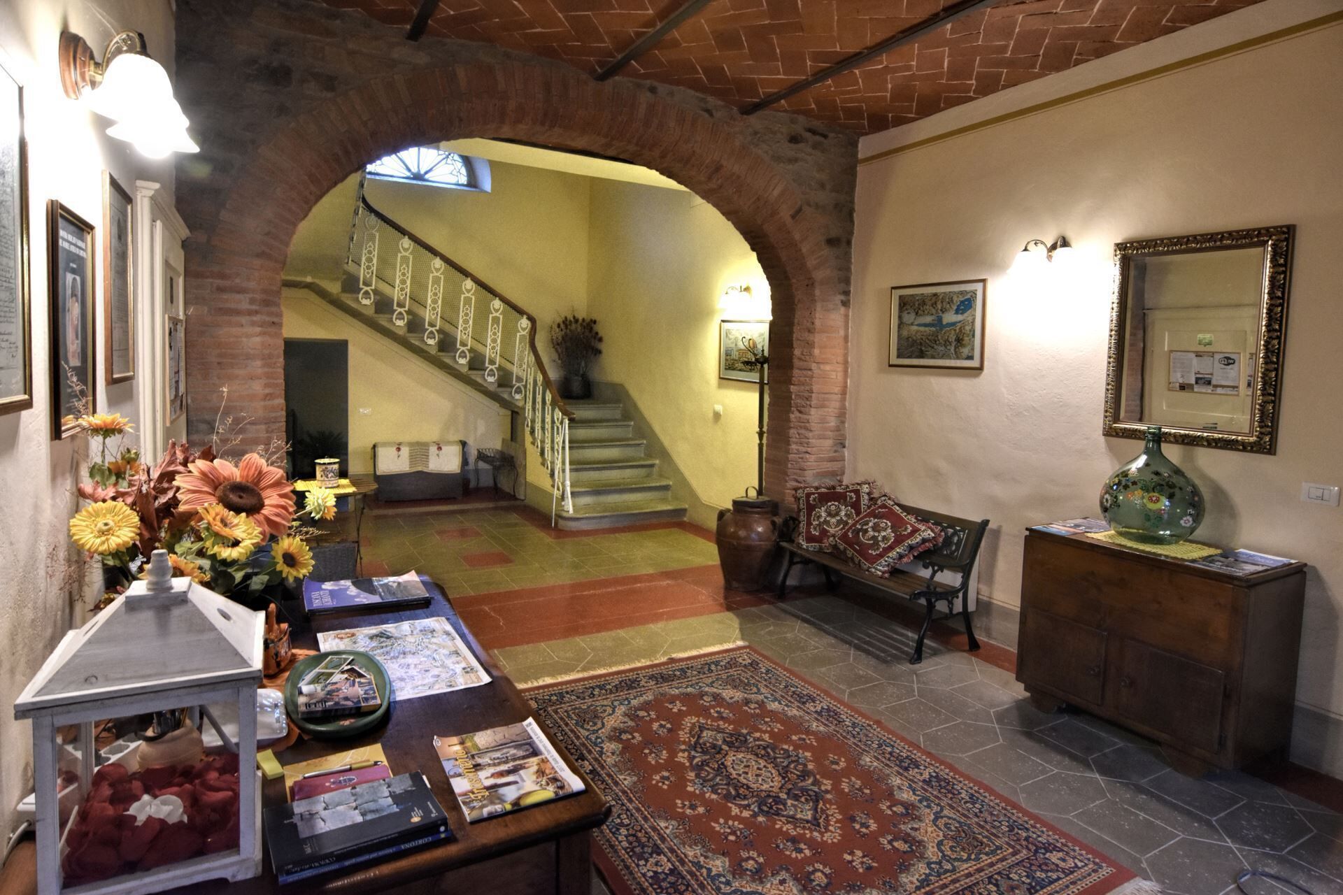 A cozy interior with a staircase, a wooden bench, a vase, and a rug.