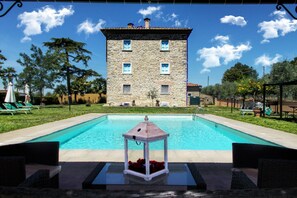 Ein Gebäude aus Stein mit einem Pool davor.