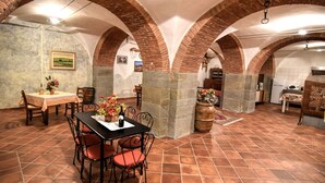 Een eetruimte met een plafond van baksteen, een tafel met stoelen en een keuken op de achtergrond.