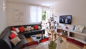 A modern living room with a black sofa, red cushions, a glass coffee table, and a TV mounted on the wall. - Beachfront Apartment Barbara, near Bacvice beach walking distance from old town  (Split)