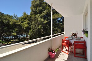 A balcony with a white railing, a table set for dining, red chairs, and a potted plant. - Beachfront Apartment Barbara, near Bacvice beach walking distance from old town  (Split)