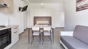 Un espacio habitable compacto con kitchenette, comedor y sofá.