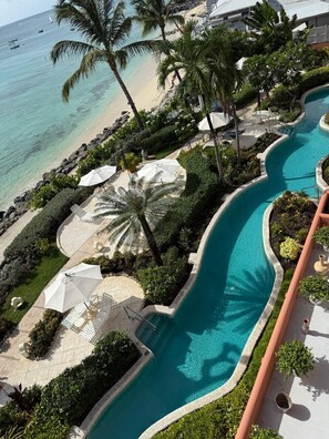 A resort with a swimming pool, palm trees, and a beach view.