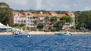 Ein Strandhotel mit mehreren Balkonen, einem Poolbereich und Booten auf dem Wasser.