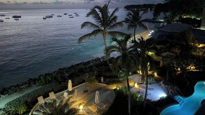 Ein Resort mit Pool, Liegestühlen und Blick auf den Ozean im Abendlicht.