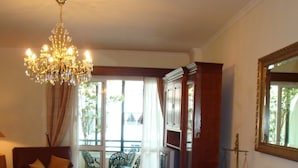 A room with a chandelier, a dining table with chairs, a red rug, a television, and a large mirror on the wall. - Funchal beach area - Sea view - Free Wifi (Funchal)