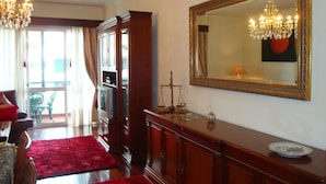 A living room with a red rug, wooden furniture, a chandelier, and a large mirror on the wall. - Funchal beach area - Sea view - Free Wifi (Funchal)