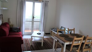 A living room with a red sofa, a white table, and a wooden dining table with chairs.