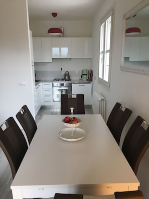 Una cocina moderna con armarios blancos, estufa a gas y cafetera.