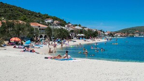 A beach with people sunbathing and swimming, surrounded by houses and a clear blue sky. - Luxury villa with heated pool, Marina-Trogir (Pozorac, Marina)