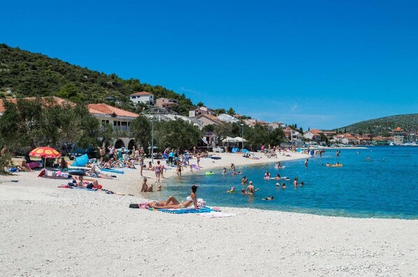 A beach with people sunbathing and swimming, surrounded by houses and a clear blue sky. - Luxury villa with heated pool, Marina-Trogir (Pozorac, Marina)