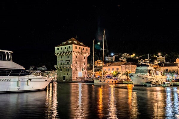 Una marina con barcos amarrados, una torre destacada y edificios al fondo.