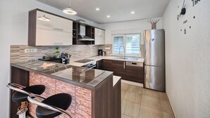 A modern kitchen with a central island, stainless steel appliances, and a clock on the wall. - Luxury villa with heated pool, Marina-Trogir (Pozorac, Marina)