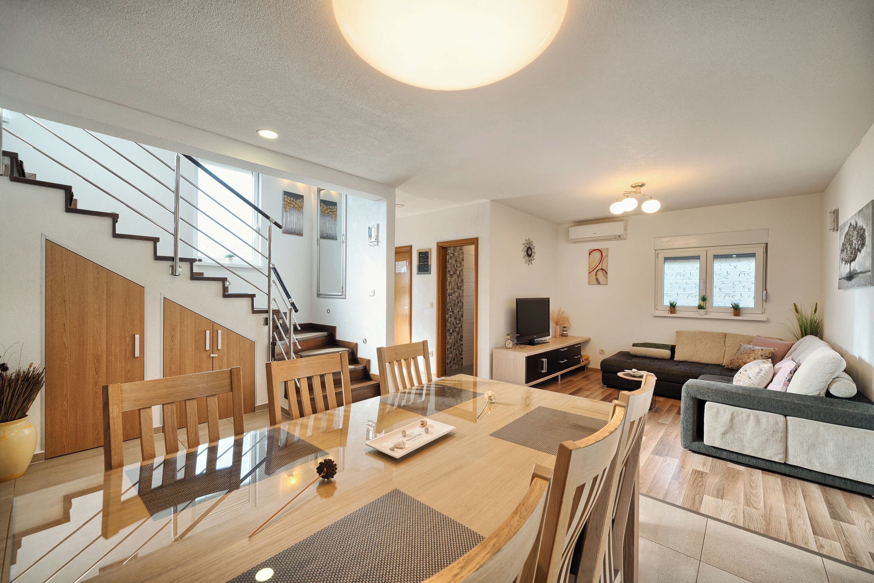 A modern living space with a dining area, staircase, and seating area.
