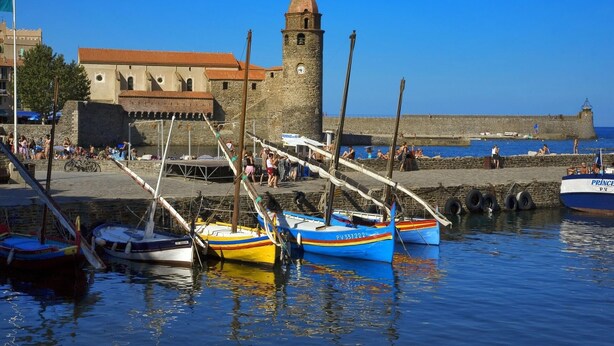 Un puerto con barcos amarrados, una torre de piedra y un edificio de techo rojo.