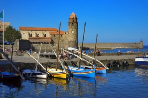 A harbor with boats docked, a stone tower, and a building with a red roof.
