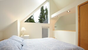 A bedroom with a bed, a nightstand, a lamp, a wooden door, and a skylight. - River Glen Streamside Condo: Stroll To Main St, Shuttle Stop (Frisco)
