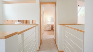 A narrow hallway with wooden railings, leading to a bedroom with a bed and a nightstand. - River Glen Streamside Condo: Stroll To Main St, Shuttle Stop (Frisco)