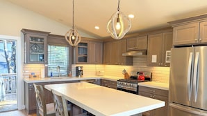 A modern kitchen with a central island, stainless steel appliances, and pendant lighting. - Captain's House ~ amazing ocean view, 2 min walk to beach, near Cannon Beach (Arch Cape)