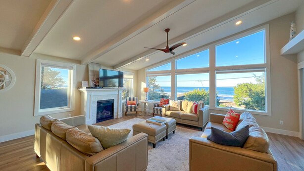 A spacious living room with a fireplace, comfortable seating, and large windows offering ocean views. - Captain's House ~ amazing ocean view, 2 min walk to beach, near Cannon Beach (Arch Cape)