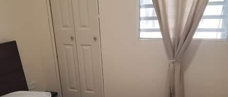 Un dormitorio con una cama, una puerta y una ventana con cortinas.