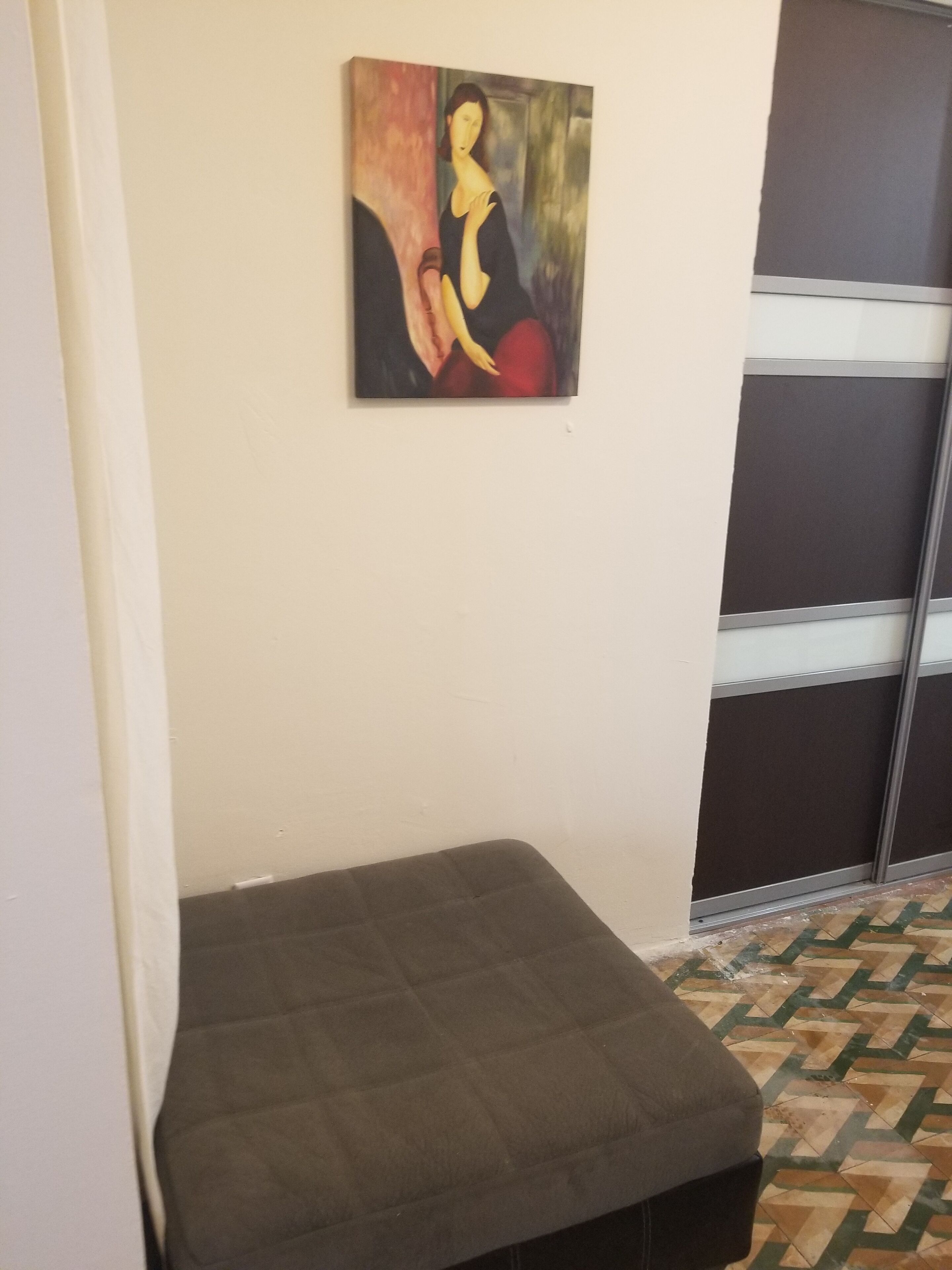 Una habitación con una cama, un cuadro en la pared y un suelo estampado.