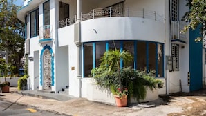 Un bâtiment à deux étages, doté d’une façade blanche et de touches de couleur bleue, avec de grandes fenêtres et un balcon.
