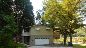 Ein zweistöckiges Gebäude mit Garage, überdachter Veranda und umzäunter Garten.