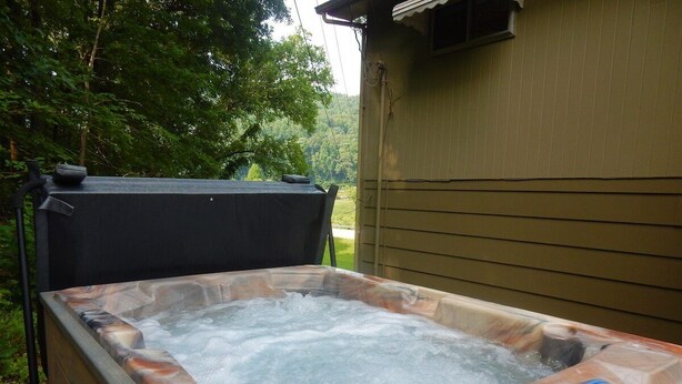 Ein Whirlpool mit Bedienfeld, umgeben von einer Holterrasse und einem Haus im Hintergrund.