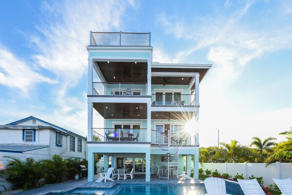 Una casa de varios pisos con piscina, balcones y zona de estar al aire libre.