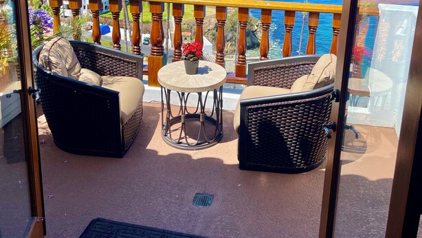 A balcony with wicker furniture, a small round table, and a view of the ocean. - Hamilton Cove ocean front luxury Villa Spectacular Views w/electric cart (Avalon)