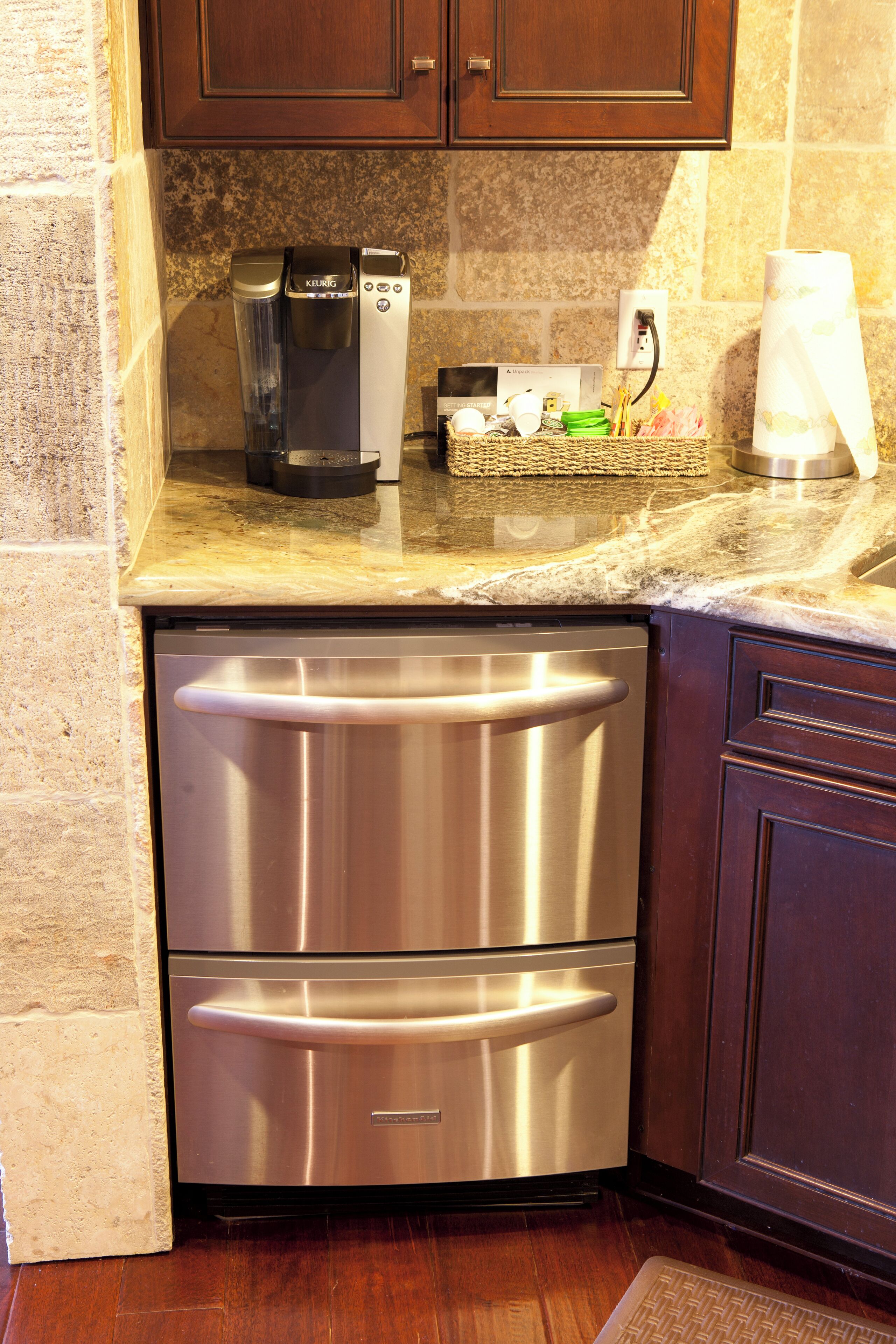 Una cocina con electrodomésticos de acero inoxidable, una cafetera y un dispensador de toallas de papel.
