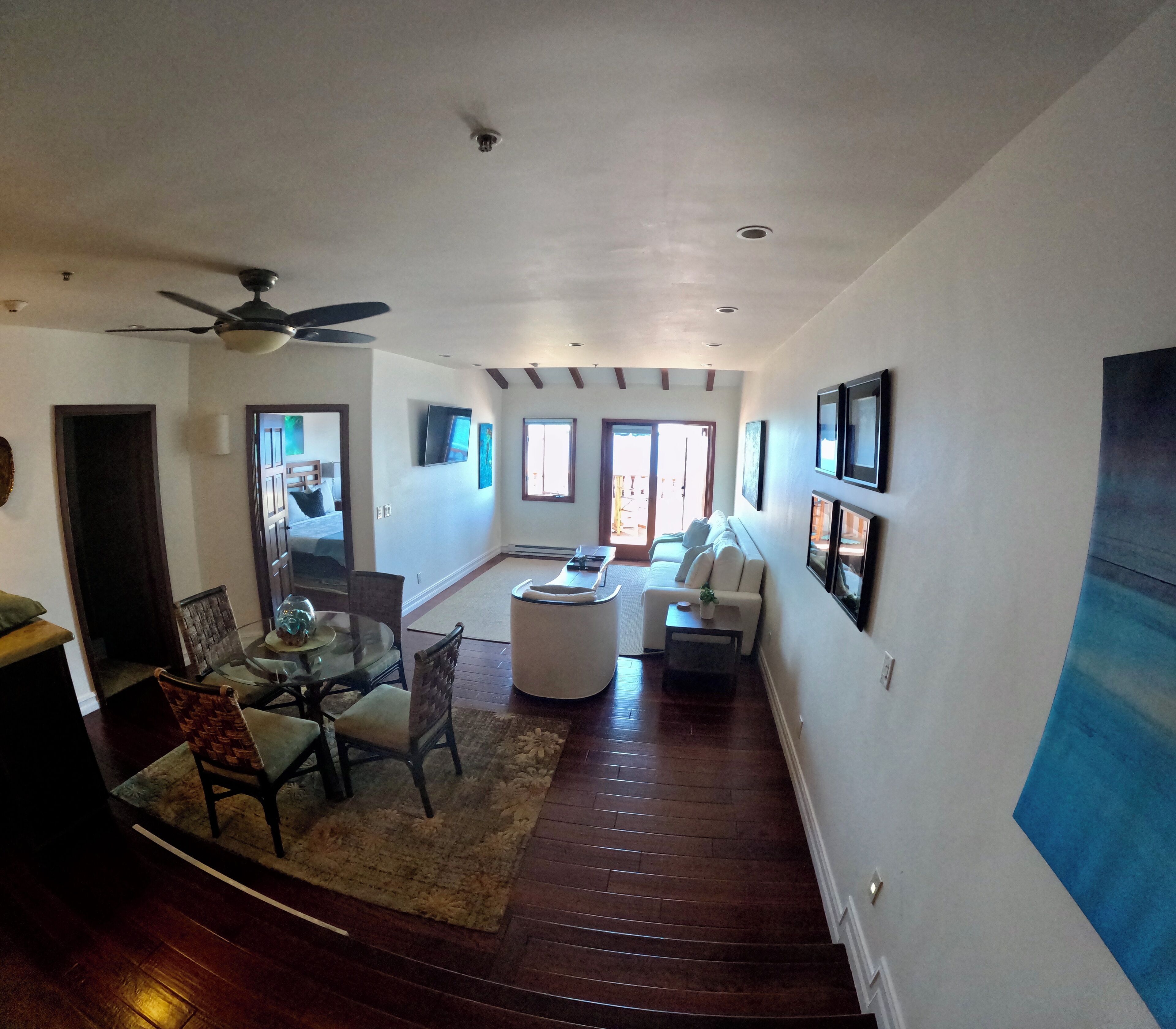 A spacious living room with a ceiling fan, a dining area with a glass table, and a staircase leading to another level.