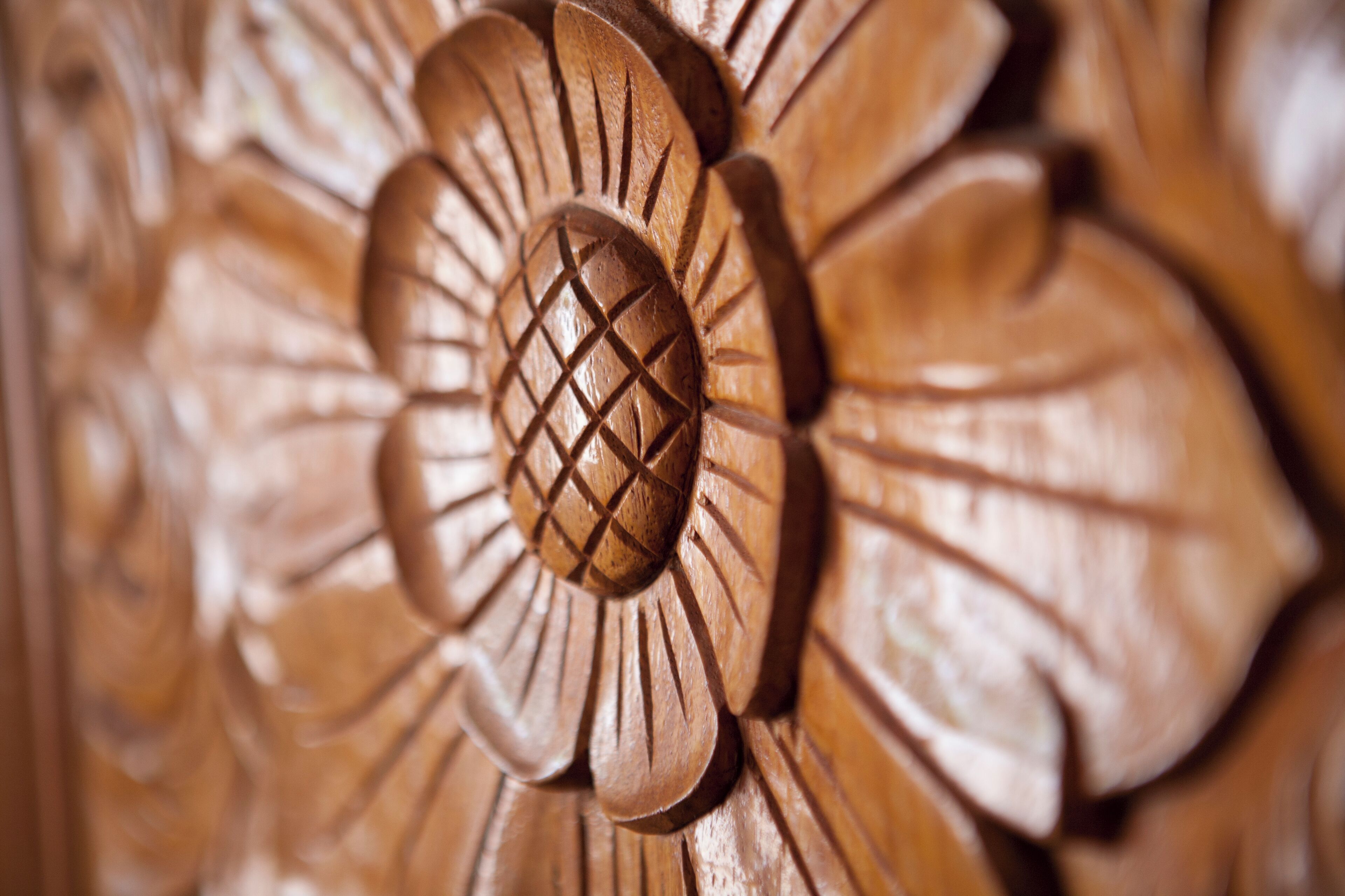 Un gros plan d’une sculpture sur bois représentant un motif circulaire central, entouré de formes évoquant des pétales.