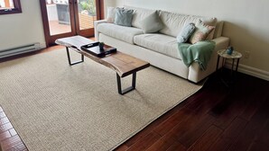 A living room with a sofa, a coffee table, a small side table, and a painting on the wall. - Amazing Luxury ocean front Hamilton Cove Villa  w/electric cart (Avalon)