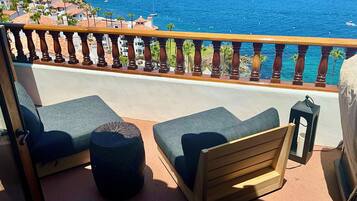 Un balcon avec des sièges d’extérieur, une vue sur la mer et une balustrade.