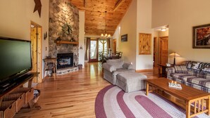 Una sala de estar acogedora con chimenea, pisos de madera y televisor.